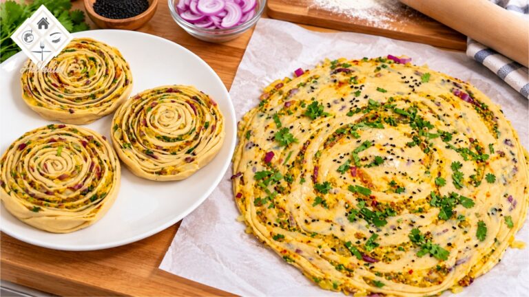 Uncooked onion lachha paratha showing spiral layers filled with onions, achari spices and fresh coriander.